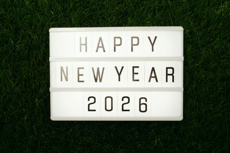 2026 Happy New Year word in light box flat lay on green grass background