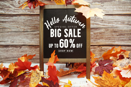 Hello Autumn Big Sale 60% text with maple leaf decoration on wooden background