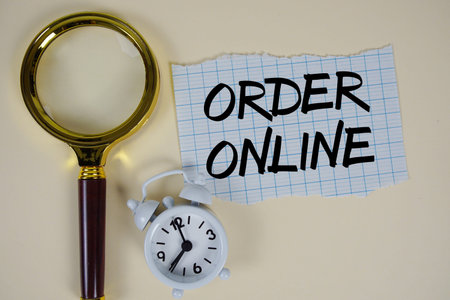 Order Online text written on paper with magnifying glass and alarm clock