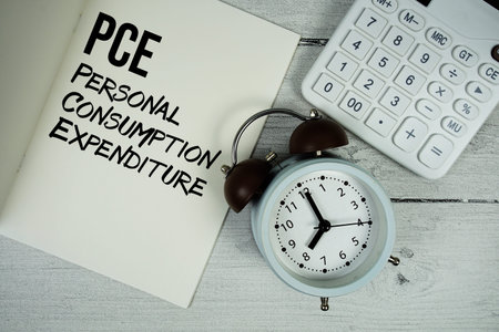 PCE Personal Consumption Expenditure text on paper notebook page with alarm clock and calculator on...