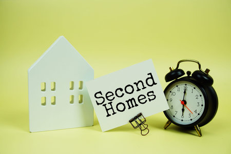 text with house model and alarm clock on yellow background
