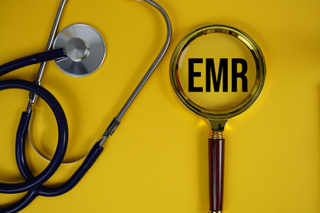 EMR abbreviation of Electronic Medical Recordstext with Stethoscope and magnifying glass flat lay on...