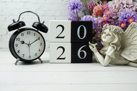Happy New Year 2026 with wood block number on wooden table background decorations with alarm clock...
