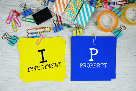 IP - Investment Property text on stick note with stationery on concrete background