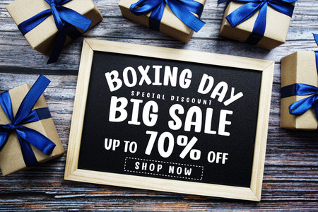 Boxing Day Big Sale 70% Off text on blackboard with present gifts on wooden background