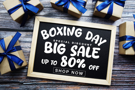 Boxing Day Big Sale 80% Off text on blackboard with present gifts on wooden background