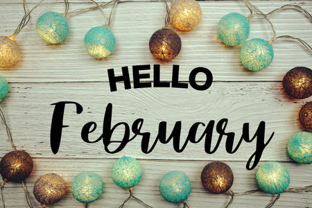 Hello February text with LED cotton balls decorated on wooden background
