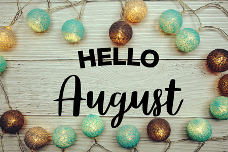 Hello August text with LED cotton balls decorated on wooden background