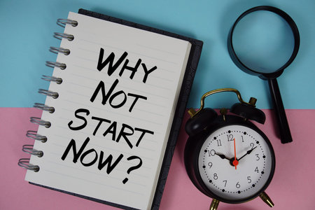 Why Not Start Now? text written on notebook paper with magnifying glass and alarm clock