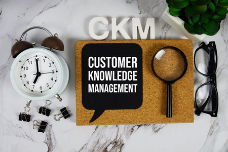 CKM - Customer Knowledge Management acronym with calculator, alarm clock and magnifying glass,...