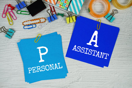 PA - Personal Assistant text on stick note with stationery on concrete background