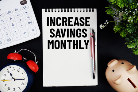 Increase Savings Monthly text with calculator with alarm clock and piggy bank on black backgroundの写真素材