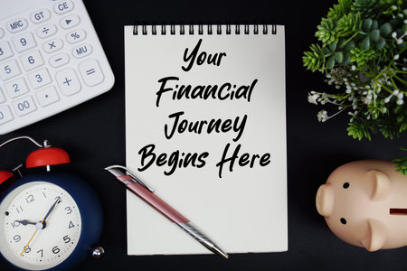 Your Financial Journey Begins Here text with calculator with alarm clock and piggy bank on black...