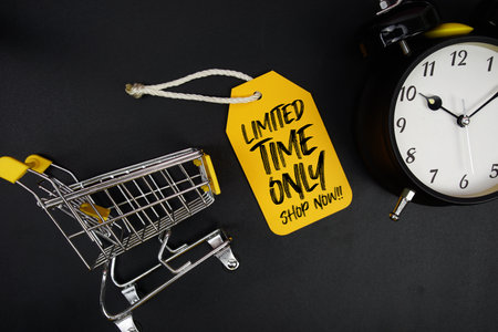 Mini Trolley Shopping Cart and price tag with message "Limited Time Only Shop Now" and alarm clock on black backgroundの写真素材