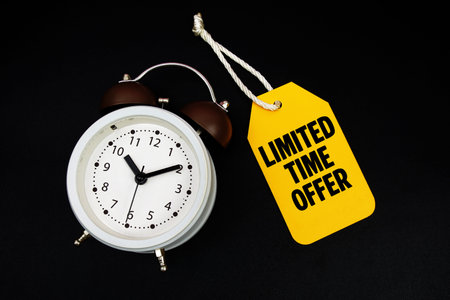 Price tag with message Limited Offer and alarm clock on black background