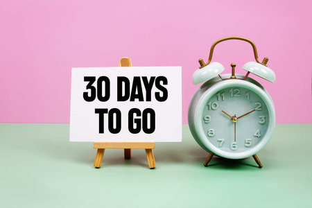30 Days To go text with alarm clock on pink and green backgroundの写真素材