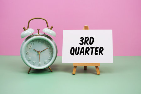 Third Quarter text with alarm clock on pink and green backgroundの写真素材
