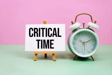 Critical Time text with alarm clock on pink and green background