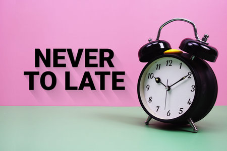 Black alarm clock on a pastel green and pink background with the text Never To Late