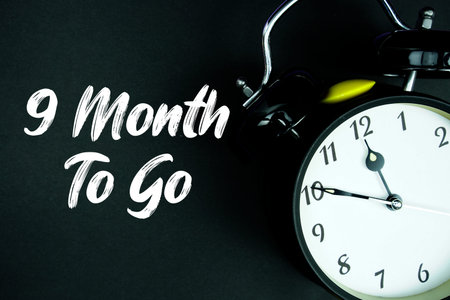 9 Month To Go text and alarm clock on black backgroundの写真素材
