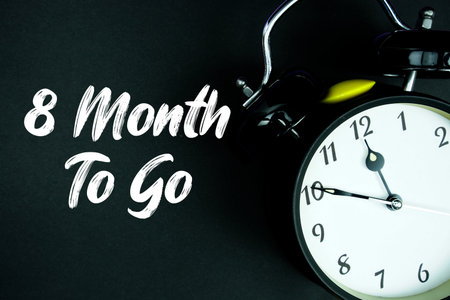 8 Month To Go text and alarm clock on black backgroundの写真素材