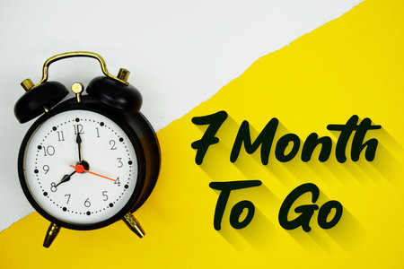 7 Month To Go text and alarm clock on yellow background