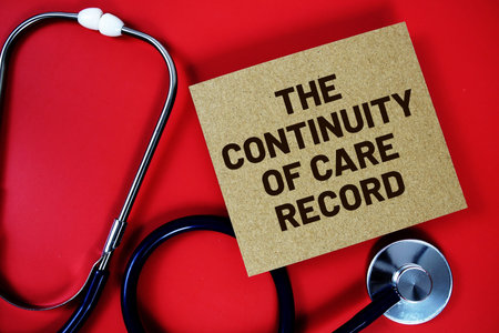 The Continuity of Care Record text written on paper card with stethoscope on red backgroundの写真素材