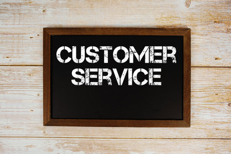 Customer Service text written on blackboard flat lay on wooden backgroundの写真素材