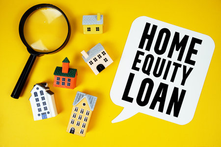 Home Equity Loan text with house models and magnifying glass on yellow backgroundの写真素材