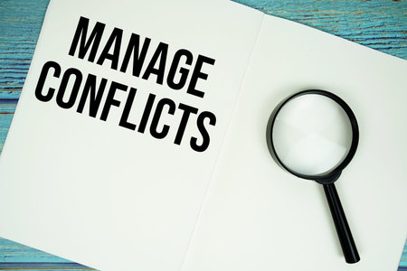 Manage Conflicts text written on notepad with magnifying glass flat lay on wooden background