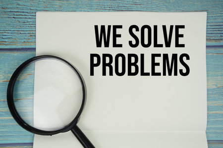 We Solve Problems text written on notepad with magnifying glass flat lay on wooden background