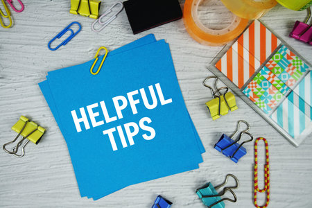 Helpful Tips text on stick note with stationery on concrete background