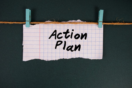 Action Plan text written on rip paper with wooden clip on dark green background