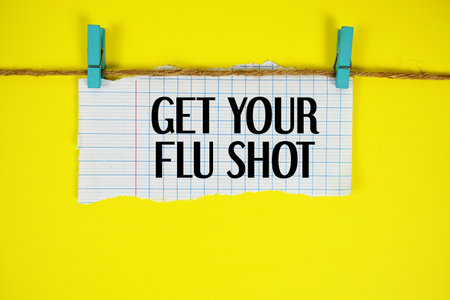 Get Your Flu Shot text written on rip paper with wooden clip on yellow backgroundの写真素材