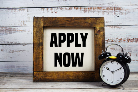 Apply  Now text with alarm clock on wooden background