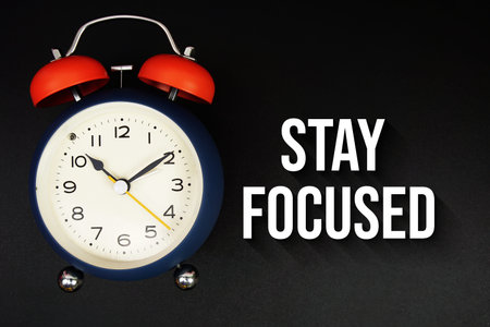 Stay Focused text with alarm clock on black background