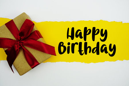 Happy Birthday text with gift box present on yellow backgroundの写真素材