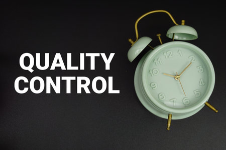 Quality Control text with alarm clock on black backgroundの写真素材