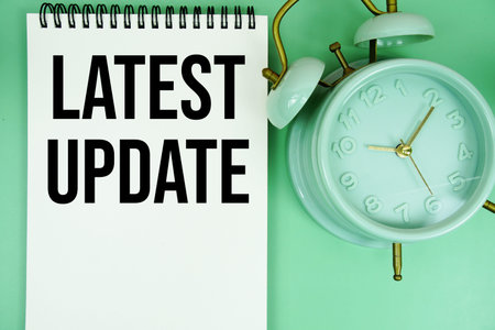 Latest Update text with alarm clock flat lay on green background