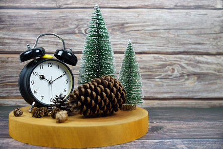 Winter-themed decor with a vintage alarm clock, pinecones, and miniature snowy trees on a wooden...