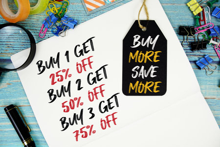 Buy 1 get 25%, Buy 2 get 50%, Buy 3 get 75% text on a notepad paper and Buy More Save More with...