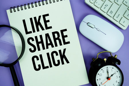 Notepad with the text "Like Share Click" and white keyboard, wireless mouse, magnifying glass and alarm clockの写真素材