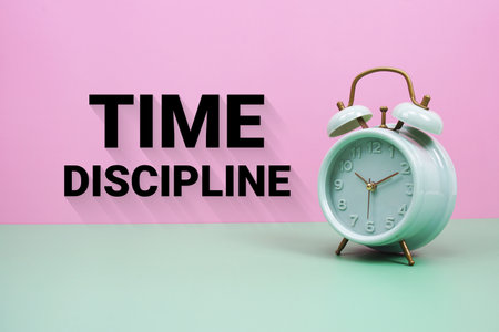 Black alarm clock on a pastel green and pink background with the text "Time Discipline"の写真素材