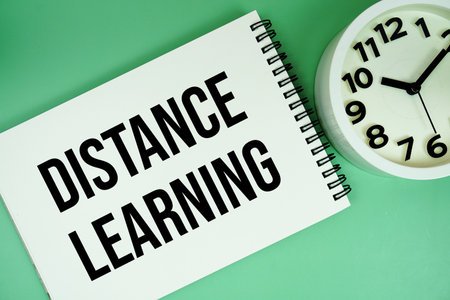 Distance Learning text with alarm clock flat lay on green backgroundの写真素材