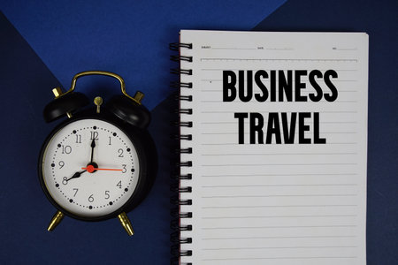 Business Travel text written on notepad with alarm clock on blue backgroundの写真素材
