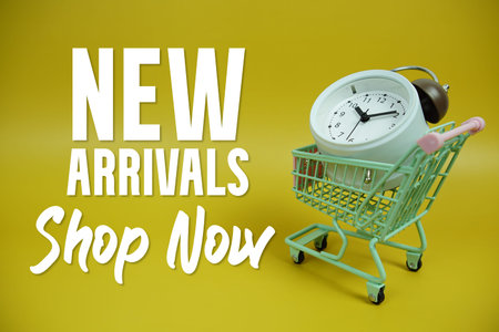 New Arrivals text with trolley shopping cart and alarm clock on yellow background