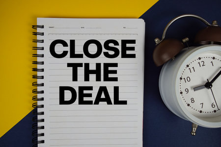 Close the Deal text written on notepad with alarm clock on yellow backgroundの写真素材