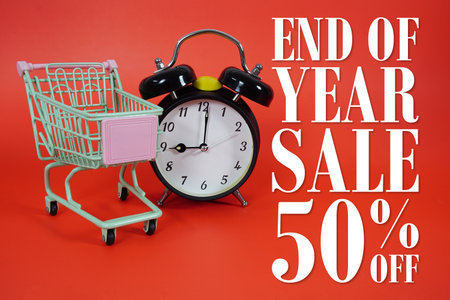 Year End Sale 50% off Promotion and Marketing with trolley shopping cart and alarm clock on red backgroundの写真素材