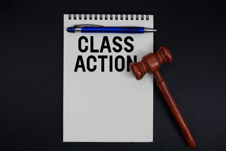 Class Action text written on notepad with gavel on black background