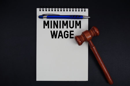Minimum Wage text written on notepad with gavel on black backgroundの写真素材